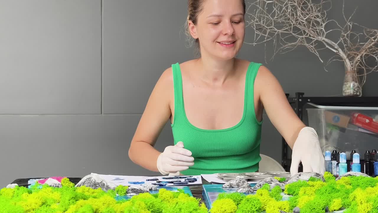 mujer creando arte de resina con decoraciones de musgo