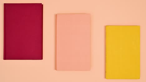 red and yellow hardcover books move from orange theme and monochrome orange book opens. stop motion flat lay