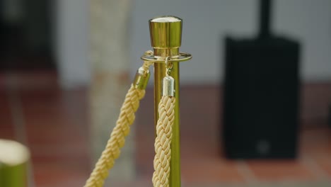 close up of a gold stanchion with a braided rope barrier in an event setup