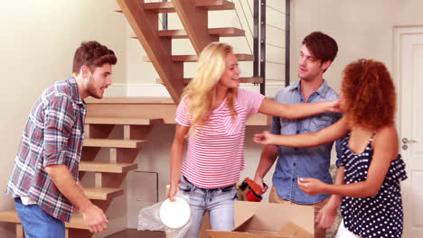 una joven y encantadora pareja desempaquetando cajas mientras son visitadas por amigos.
