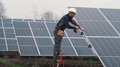 a man in a work uniform installs a solar panel at a solar power plant