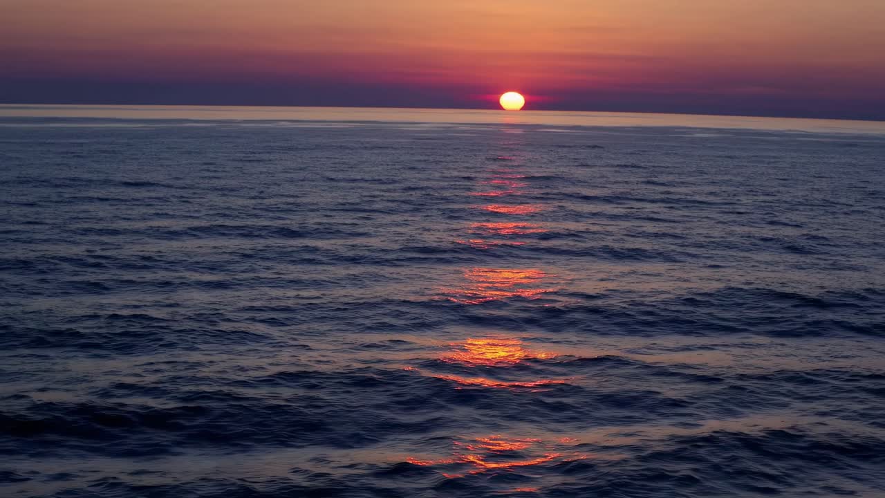 A serene sunset over the ocean captured from a low-angle, creating a tranquil video backdrop