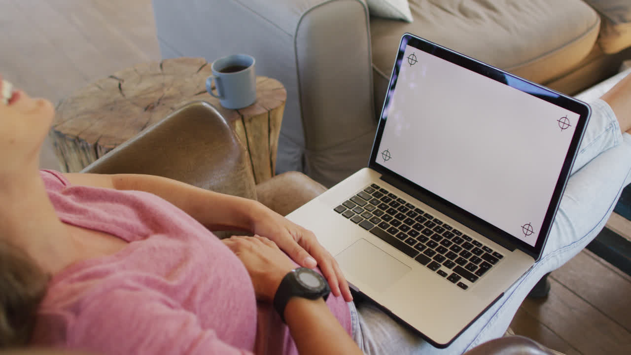 feliz mujer caucásica embarazada sentada en un sillón y usando una computadora portátil con espacio para copiar