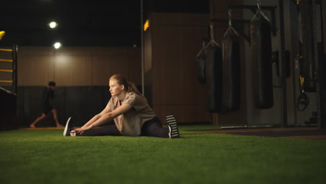 Energiegeladene-Sportlerin-Macht-Spagat-Im-Sportverein.-Fittes-Mädchen,-Das-Sich-Im-Fitnessstudio-Aufwärmt