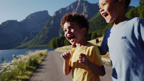 two happy boys playing by a scenic mountain lake
