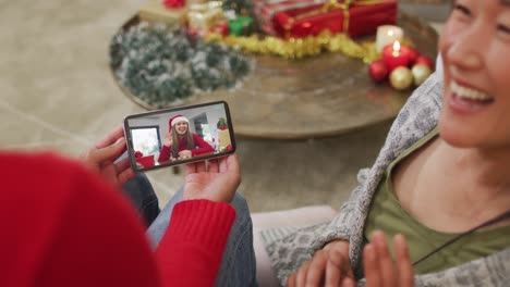 Lächelndes-Asiatisches-Paar,-Das-Sein-Smartphone-Für-Einen-Weihnachtsvideoanruf-Mit-Einer-Glücklichen-Frau-Auf-Dem-Bildschirm-Nutzt