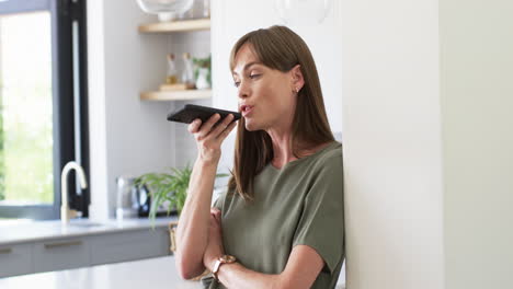 middle-aged caucasian woman using voice command on smartphone at home