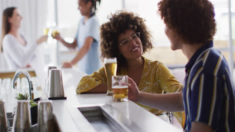 diverse group of happy friends drinking beers and talking at a bar