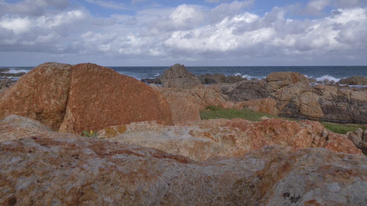 Uma vista panorâmica de uma costa rochosa com ondas oceânicas quebrando sob um céu dinâmico cheio de nuvens em Ramsgate, Costa Sul, KwaZulu-Natal.