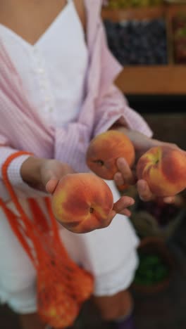 woman holding peaches at a farmer's market