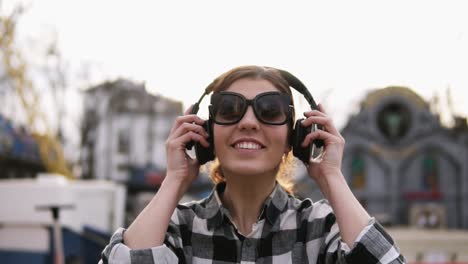 the girl is putting on the headphones and starting to move with the rhythms of the music. in sunglasses. enjoy it. slow motion