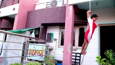 side view of a young girl hanging on a rope doing different poses of yoga and pranayama that are very difficult to do