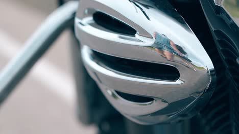 close view silver motorcycle detail reflects walking couple