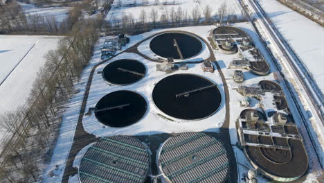 aerial of basins at sewage water treatment plant in winter - drone flying backwards