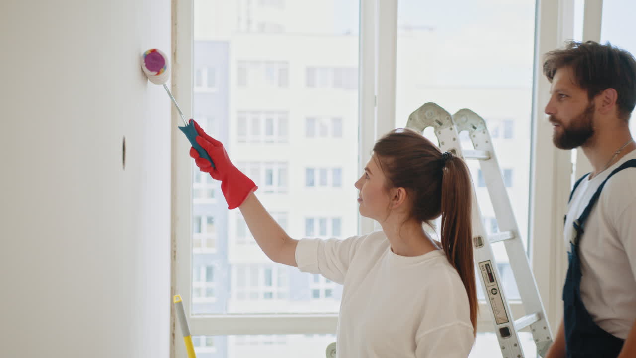 una pareja pintando una pared.