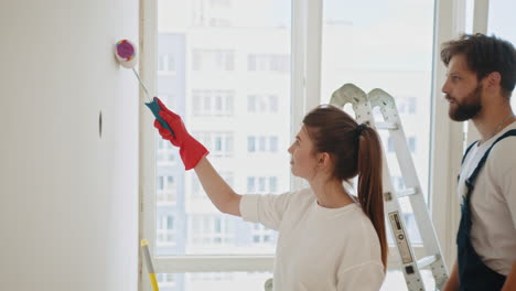 una pareja pintando una pared.