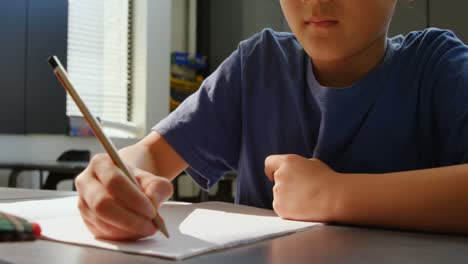 front view of attentive asian schoolboy studying at desk in classroom at school 4k