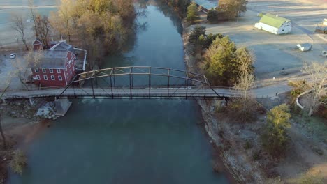 Vista-Aérea-Del-Molino-Grist-Por-El-Río-Atravesado-Por-Un-Viejo-Puente-De-Hierro