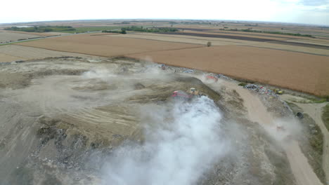 landfill operation with trucks and bulldozers in agricultural area