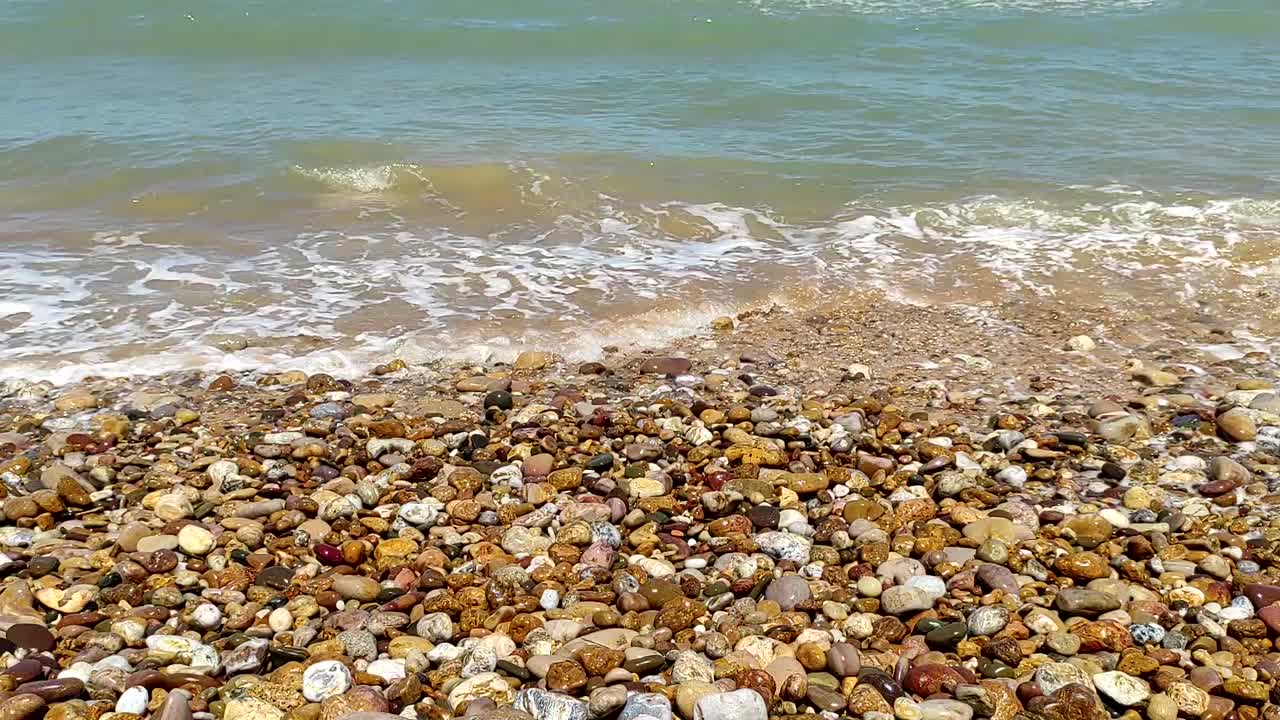 Primo piano di onde blu che si infrangono su una costa rocciosa e colorata