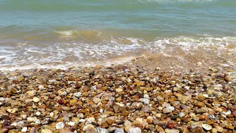 close-up blue waves breaking over a colorful rocky shoreline