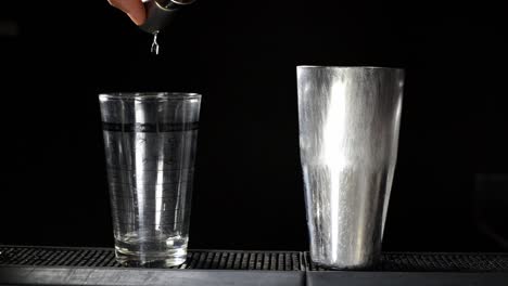 manos de barman vertiendo alcohol líquido en vidrio, agitando y mezclando cócteles de alcohol, fondo negro