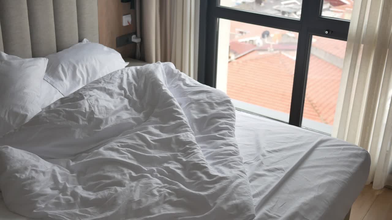 도시 전망 을 가진 현대적 인 침실 에서 만들어지지 않은 침대