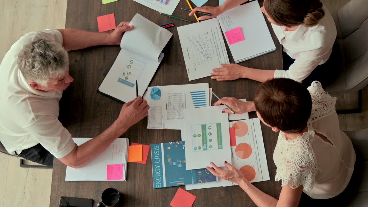 Three coworkers analysing graphs at a desk in an office