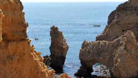 Seascape-with-rock-formation,-boat-and-kayaks-in-background