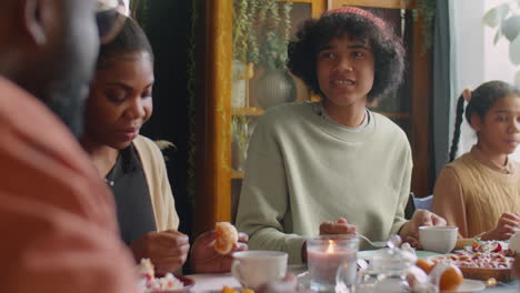 teenage boy eating cake and chatting with family at dinner