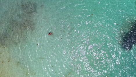 Disparo-De-Dron-En-ángulo-Descendente-De-Un-Hombre-Nadando-En-Aguas-Cristalinas-Del-Océano-Azul