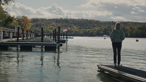 the village of a woman stands on the pier and admires lake ontaria at the end of the tourist season.