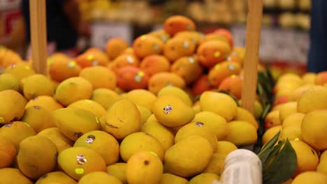 persona seleccionando naranjas de una exhibición de comestibles