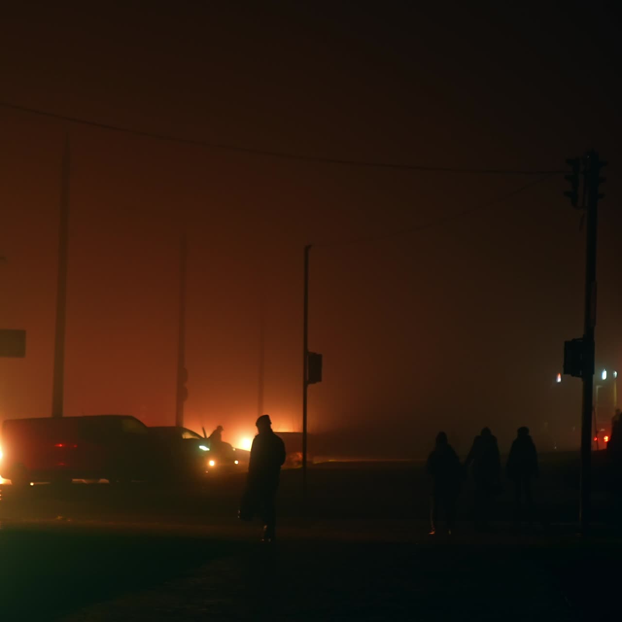 Citizens walking in the darkness by the streets at night time. Total blackout from power outage. Transport spotlights the only source of light outdoors