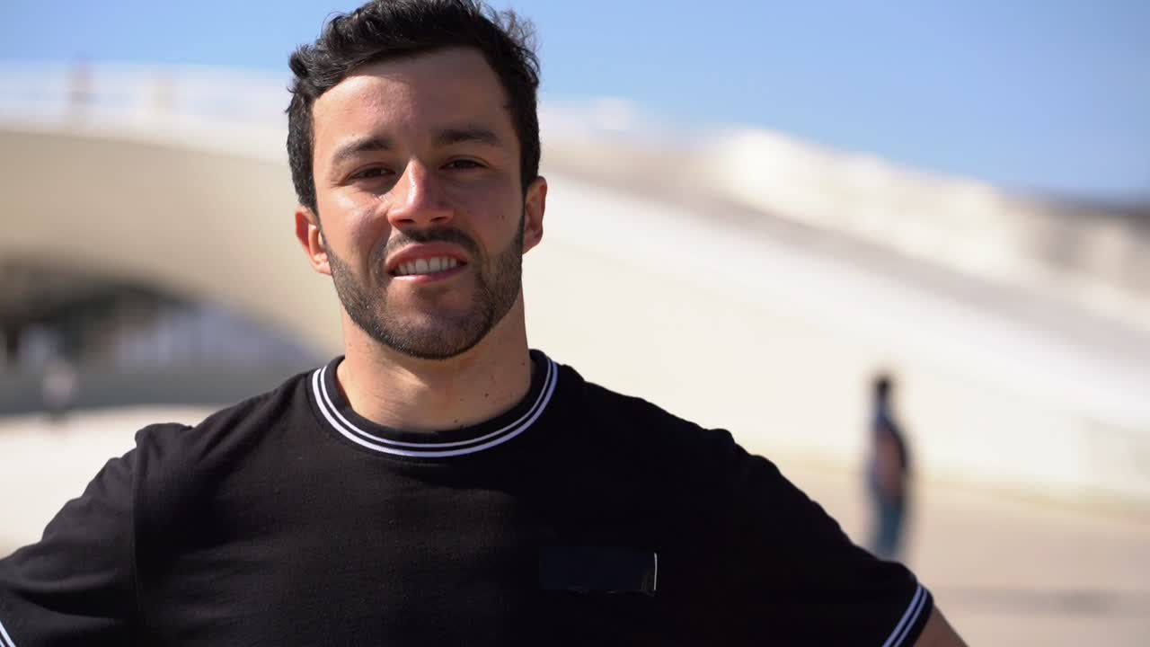 joven guapo y feliz tocando el cabello al aire libre