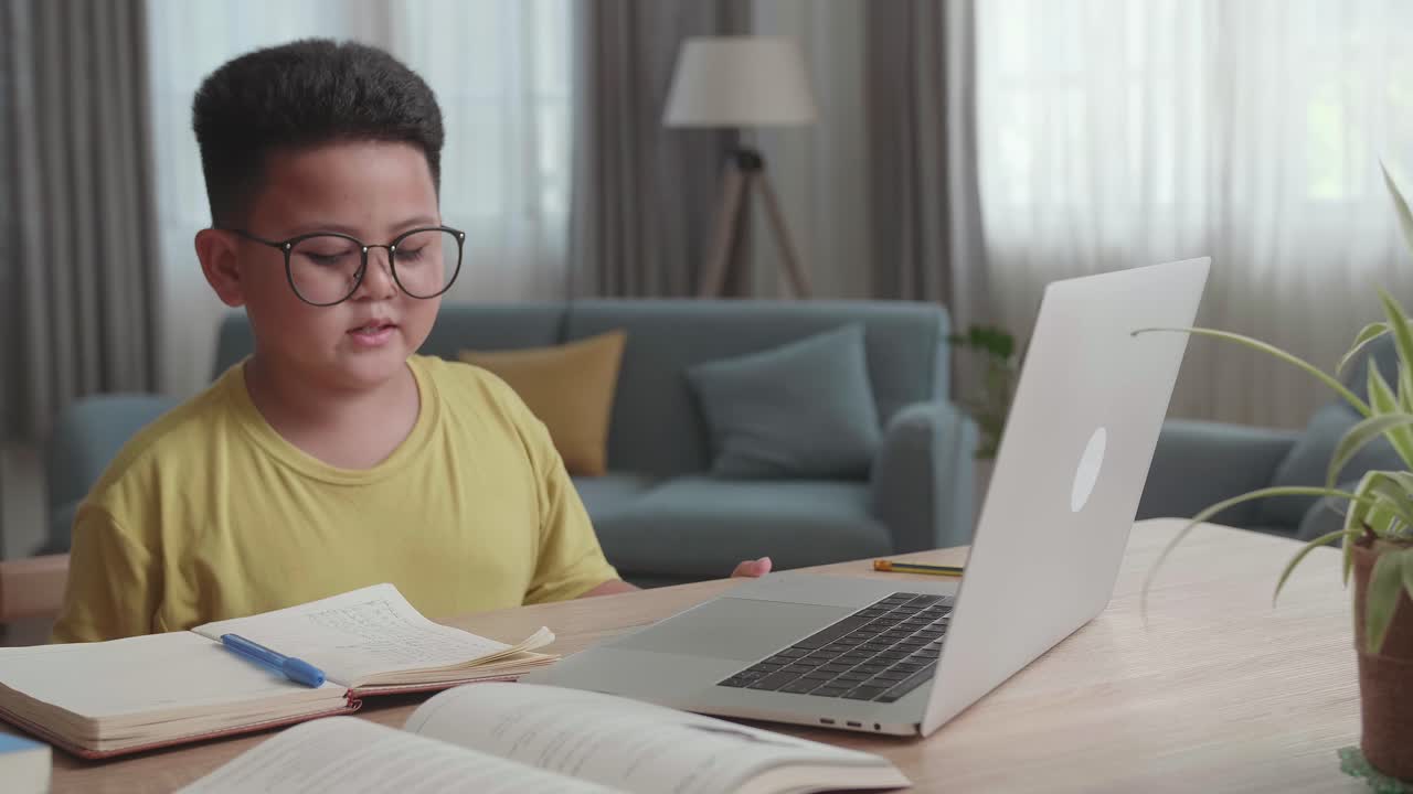 Asian Little Boy Study Online From Home. Child Use Laptop Makes Notes