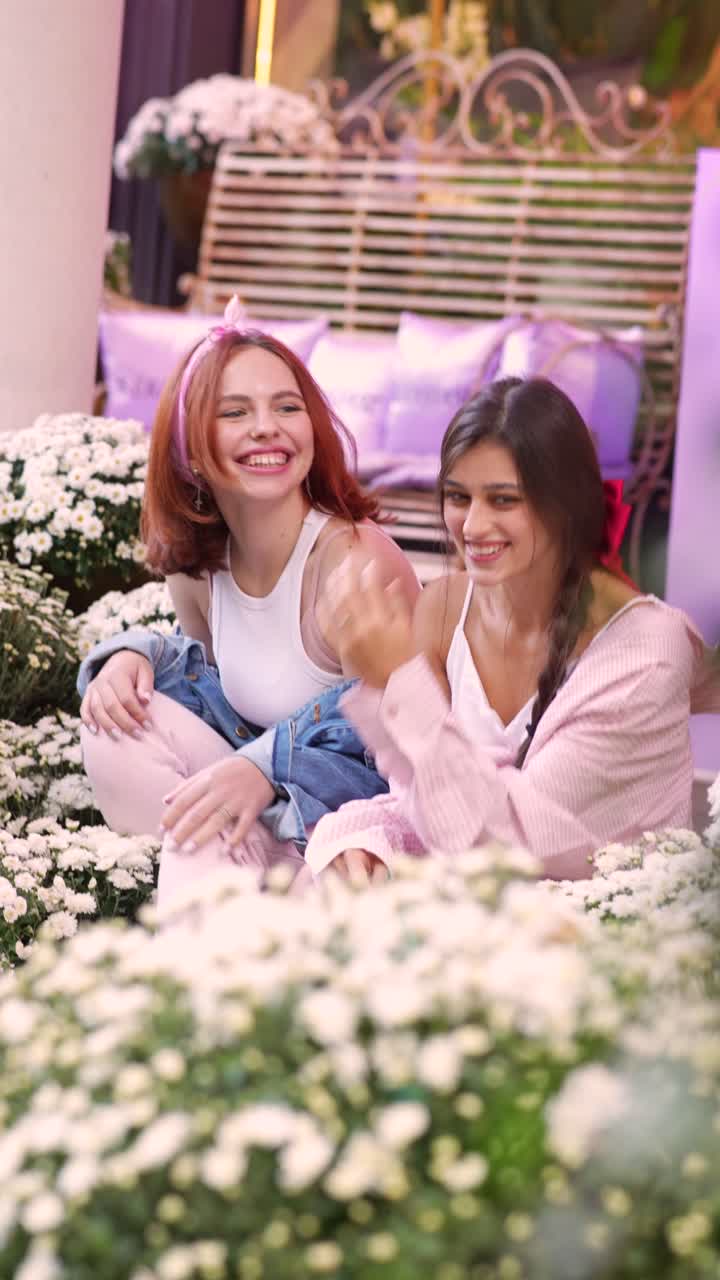 두 명의 젊은 여성들이 꽃 사이에서 야외에서 시간을 즐기고 있습니다.