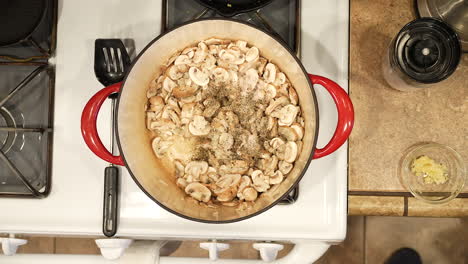 adding salt, pepper and bay leaves to sauteed mushrooms for an organic, vegan soup recipe - overhead view wild rice series