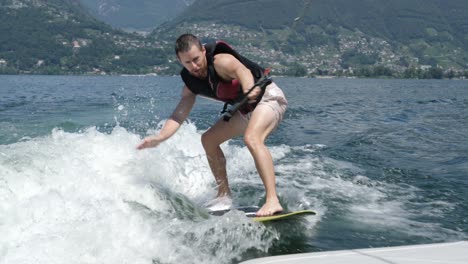 wakeboarder pulled by motorboat on lake enjoys his ride