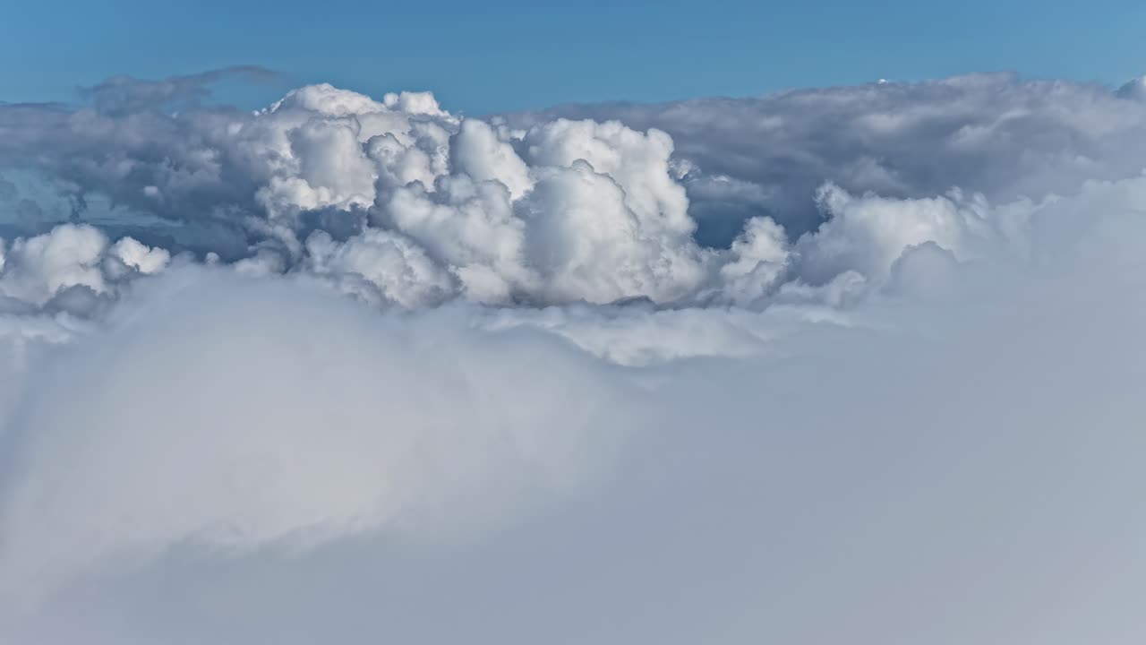 Flying above a cloud deck of cumulus clouds under a clear blue sky
