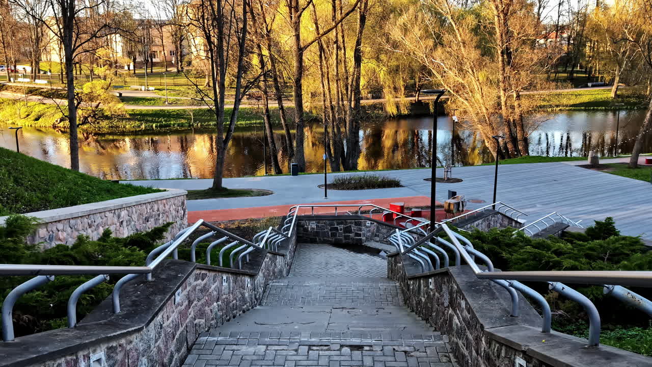 Walking down stone stairs with railings leading to riverside park area