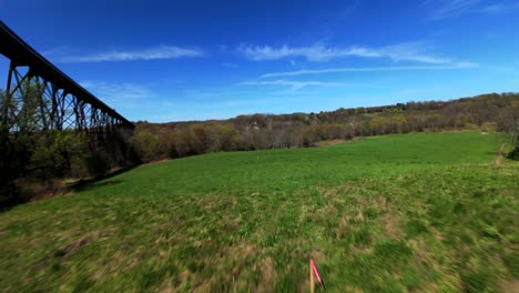 An-aerial-view-with-an-FPV-drone-flying-under-the-Moodna-Viaduct-in-Salisbury-Mills,-NY-on-a-sunny-day