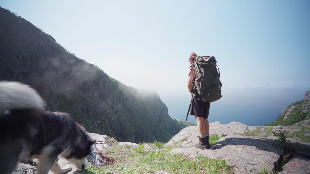 excursionista masculino se detiene en la cornisa rocosa se quita la mochila en el monte donnamannen, nordland, noruega