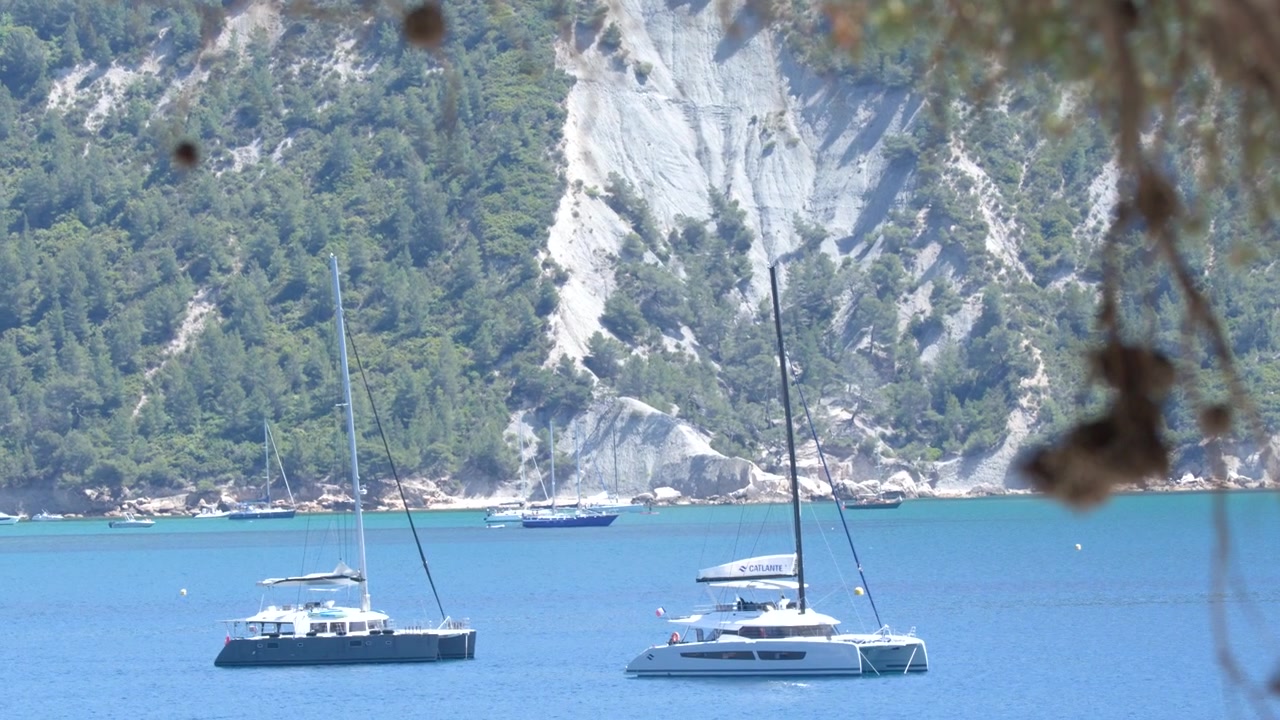 Ampia inquadratura statica di lussuose barche a vela ancorate in un mare turchese contro bianche scogliere costiere