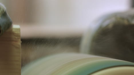 Extreme-close-up-of-wood-being-sanded-and-dust-flying-on-drum-sander---slow-motion