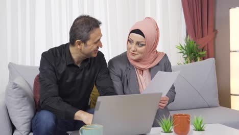 Happy-smiling-muslim-couple-sitting-on-sofa.