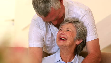 Happy-senior-couple-hugging-on-couch