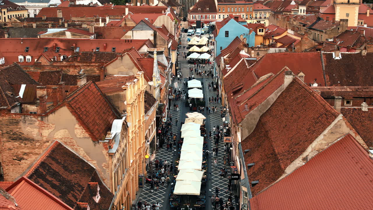 Aerial drone view of Brasov, Romania. Old city centre with pedestrian street and multiple walking people, old buildings and Black Church