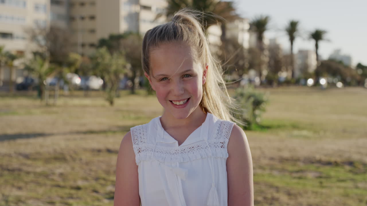 미소 짓는 예쁜 어린 소녀의 초상화 행복한 편안한 여름 휴가를 즐기는 따뜻한 일몰의 날 도시 공원 바람이 머리카락을 불어