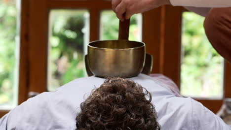 a singing bowl placed on the body is gently rubbed around its rim, filling the space with resonant vibrations during sound bath in the sacred valley, cuzco region, peru - close up